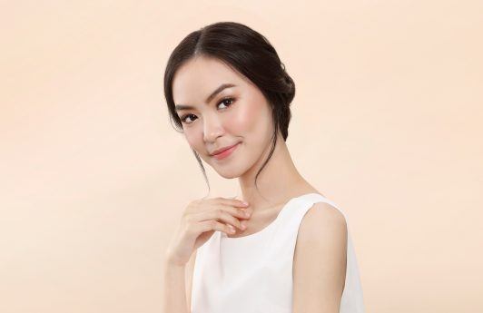Bridesmaid hairstyle: Asian woman with an elegant updo wearing a white sleeveless dress