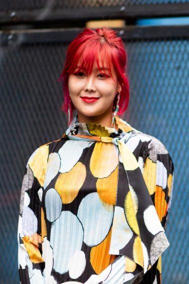 Woman with short red hair with bangs wearing a printed dress outdoors