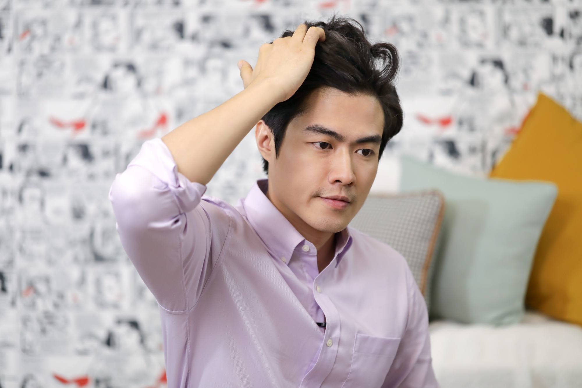 Asian man wearing a lilac polo styling his hair