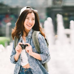 Asian woman with long hair wearing a cap and denim jacket outdoors
