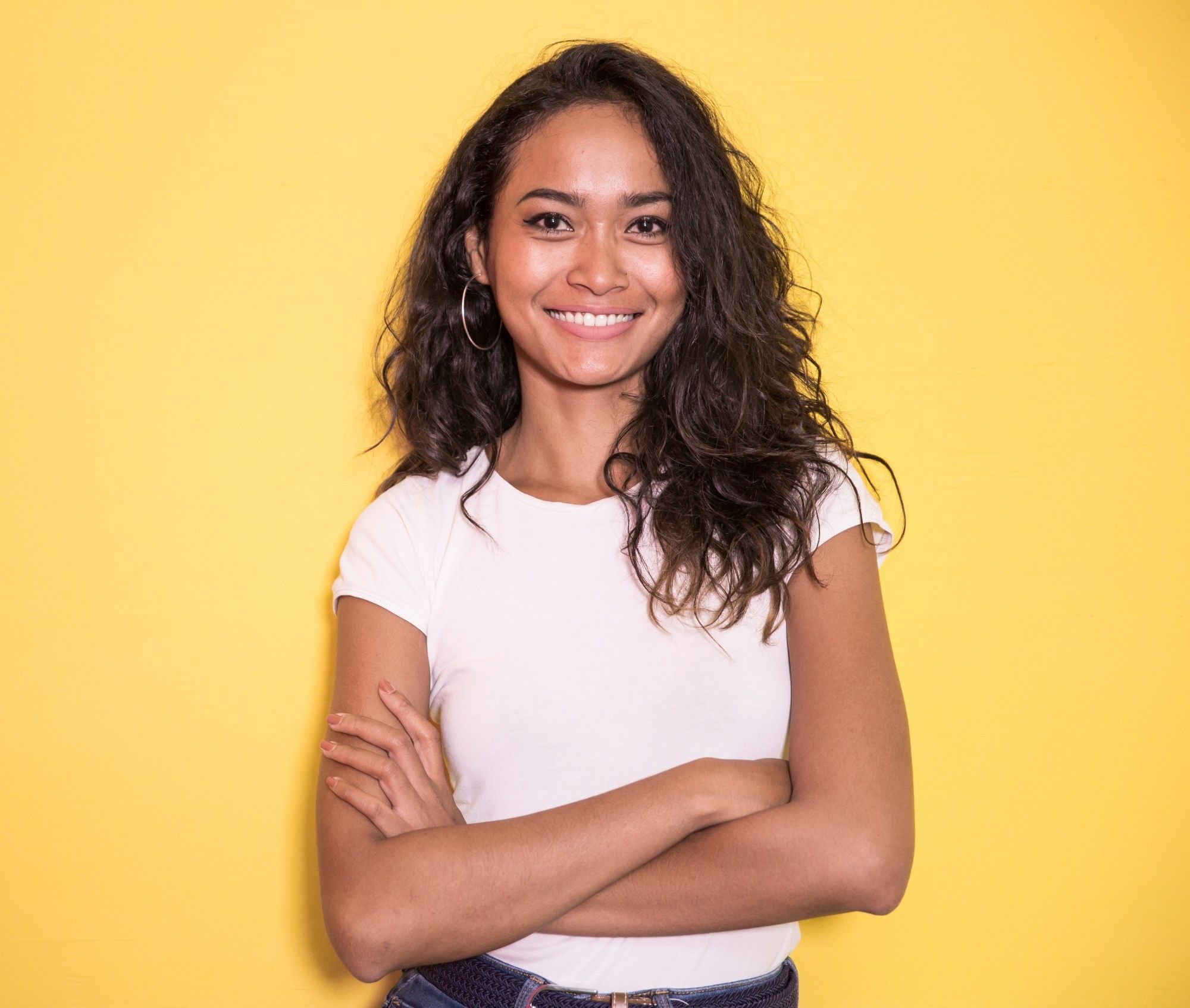 Asian woman with brown skin with dark curly hair wearing a white shirt
