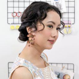 girl wears chandelier earrings with some loose strands falling to her face