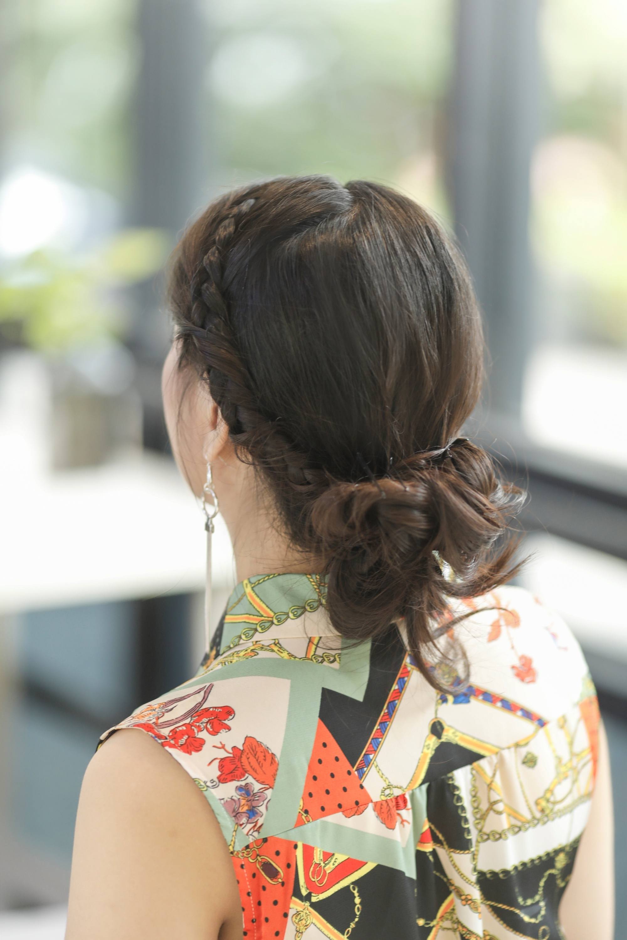 Back shot of an Asian woman with locks in a low messy bun