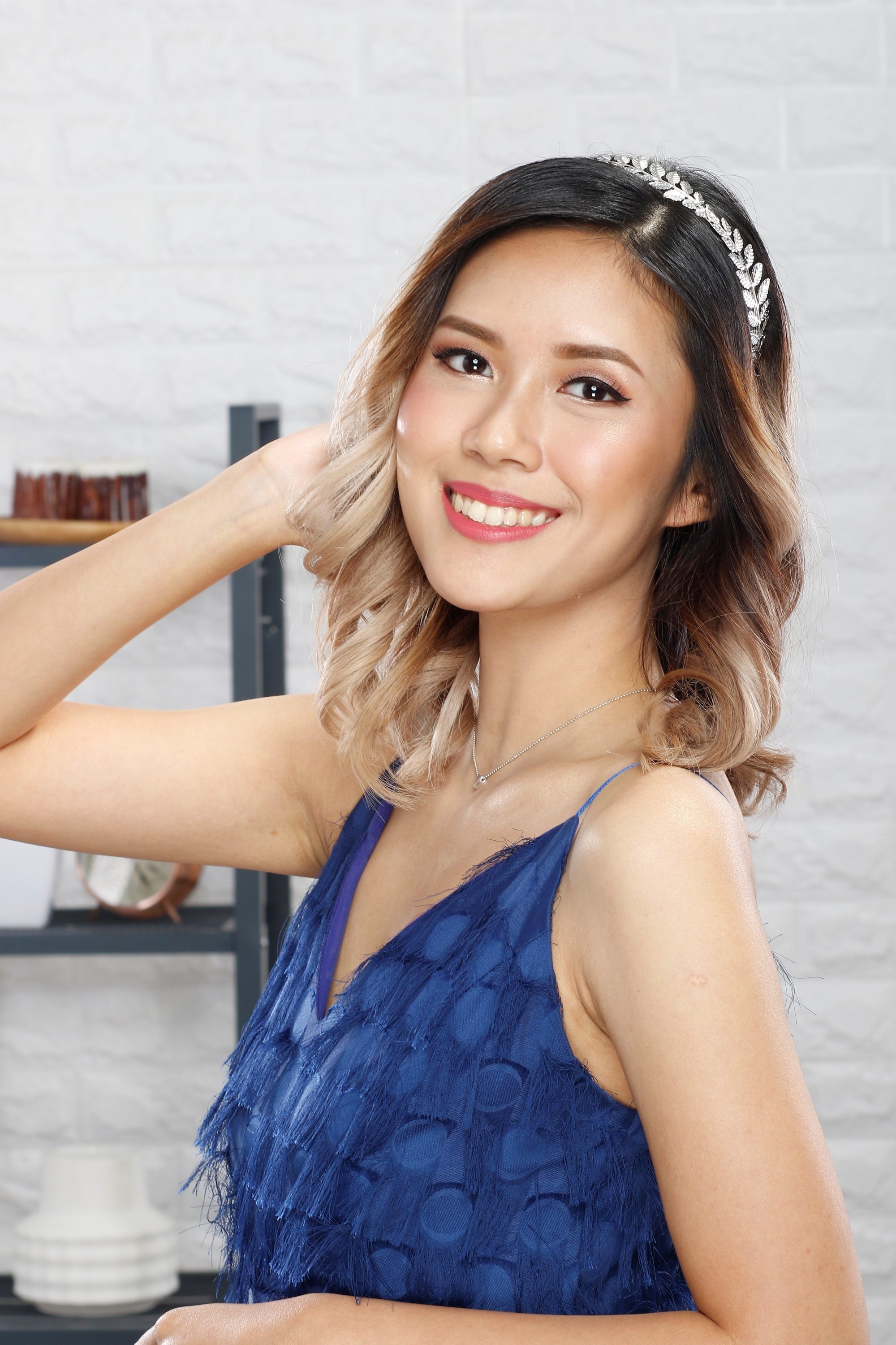 Asian woman with blonde curly hair wearing a metallic headband for prom