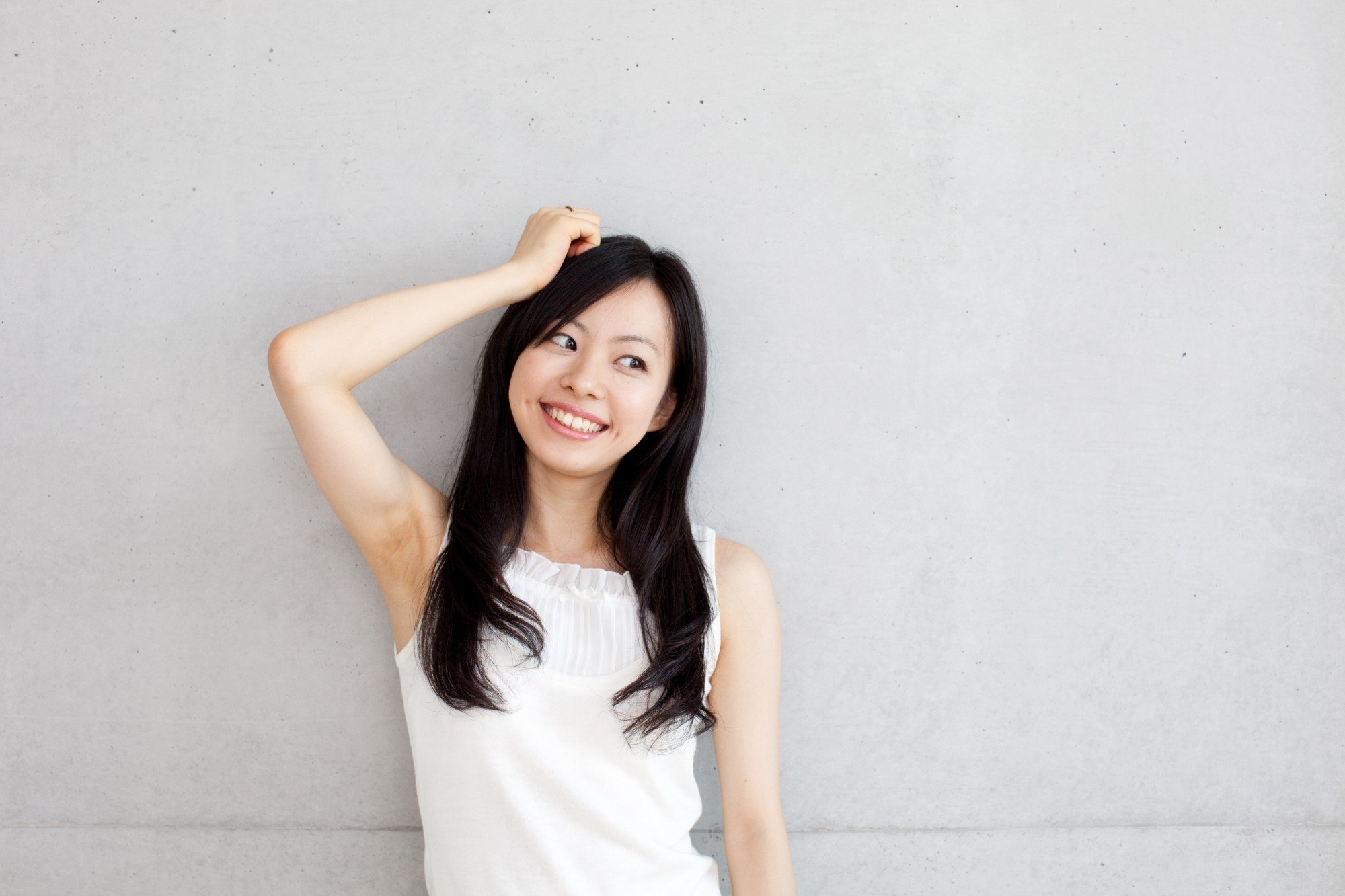 girl wearing a white dress is leaning against the wall with one hand on her hair