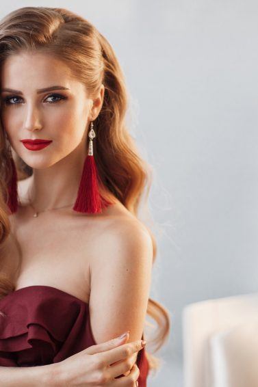 Model is wearing dangling earrings which is emphasized by her side-swept prom hair