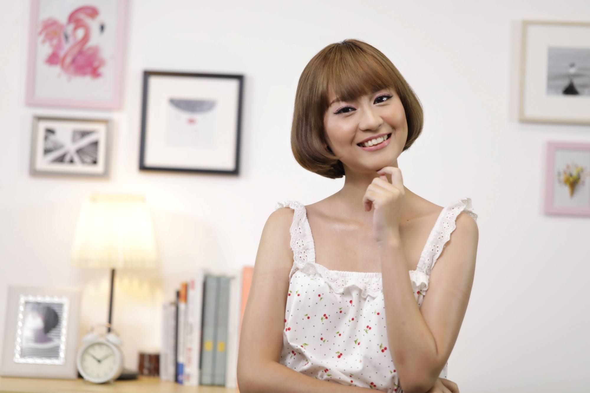 Asian woman with a chin-length bob and blunt bangs wearing a sleeveless white top