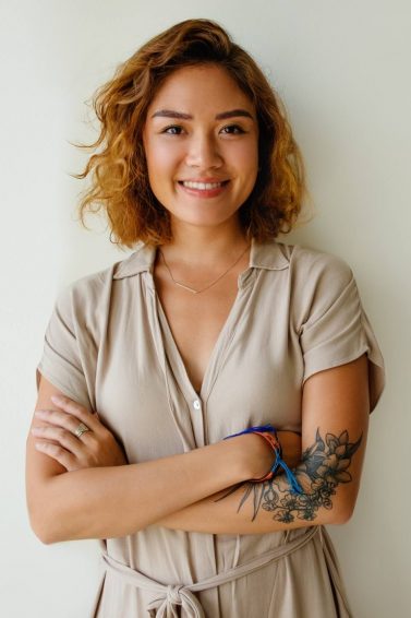 Asian woman with curly hair and honey hair color wearing a gray shirt