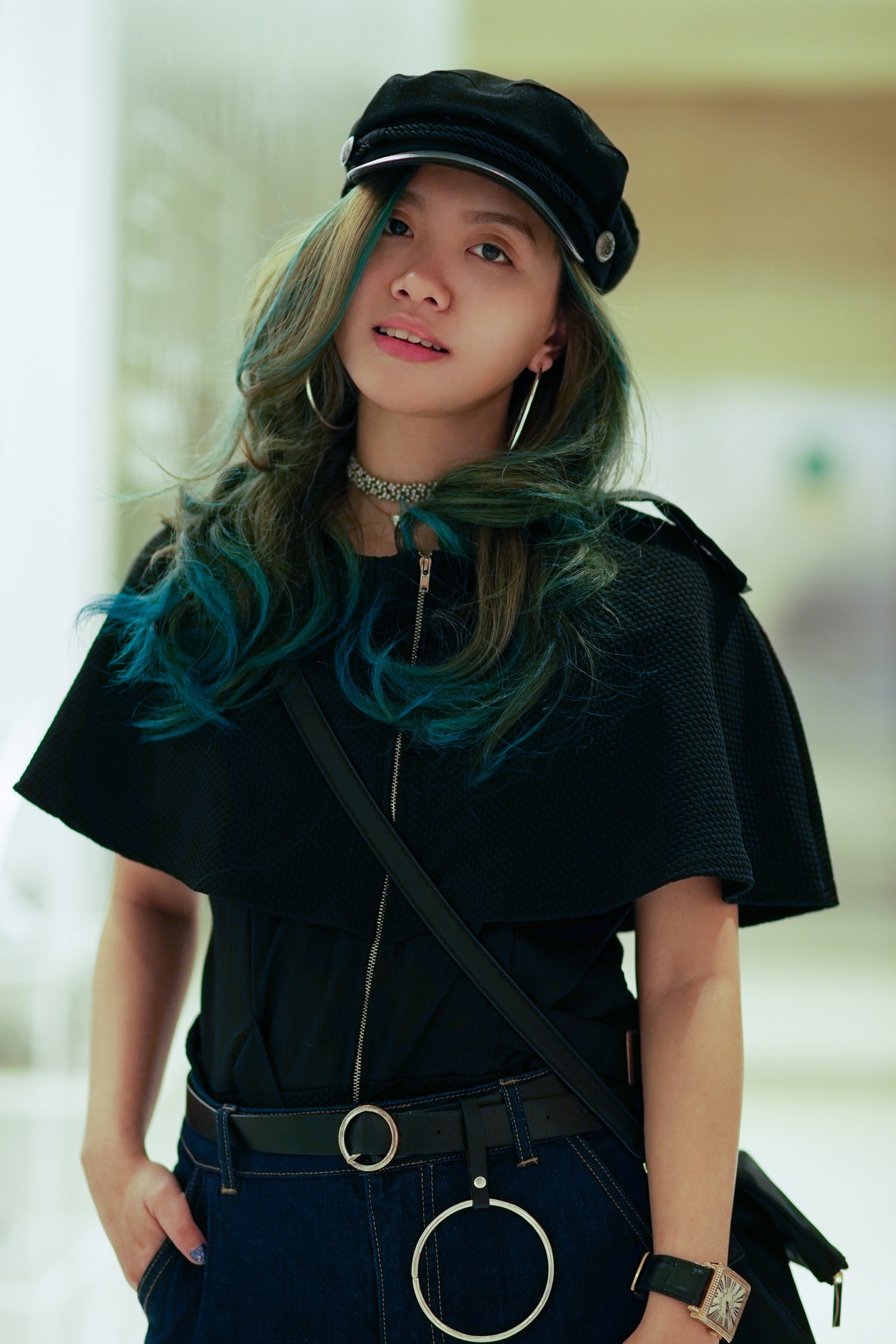 Asian woman with blue green curly hair wearing a beret