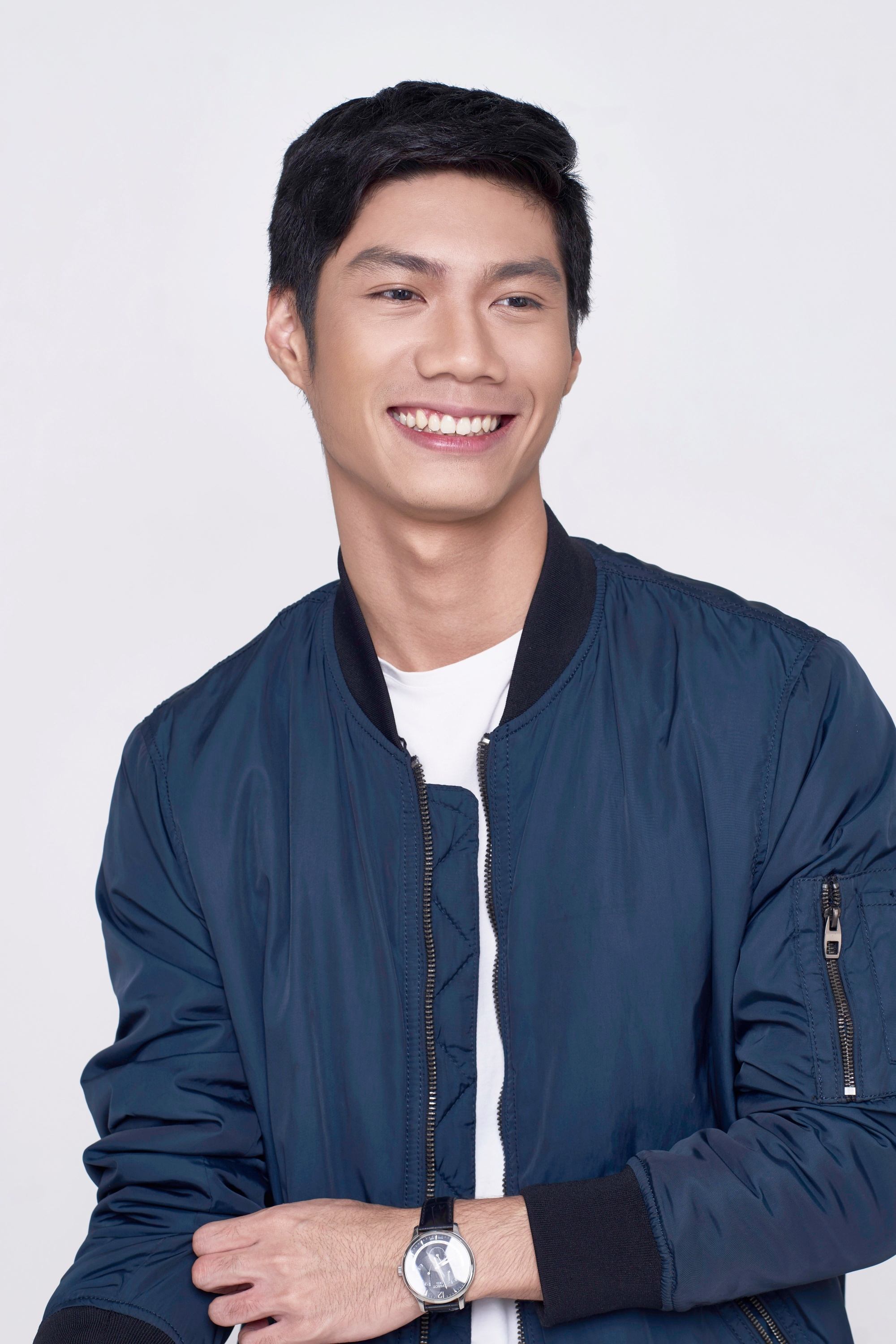 Asian man with short hair smiling and wearing a blue jacket