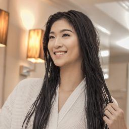 How to conserve water: Asian woman with long black hair wearing a white robe in the bathroom