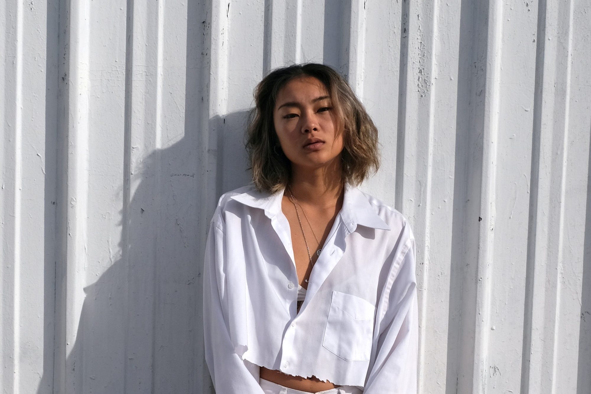 Asian woman with ash bronde hair for morena skin wearing a white polo