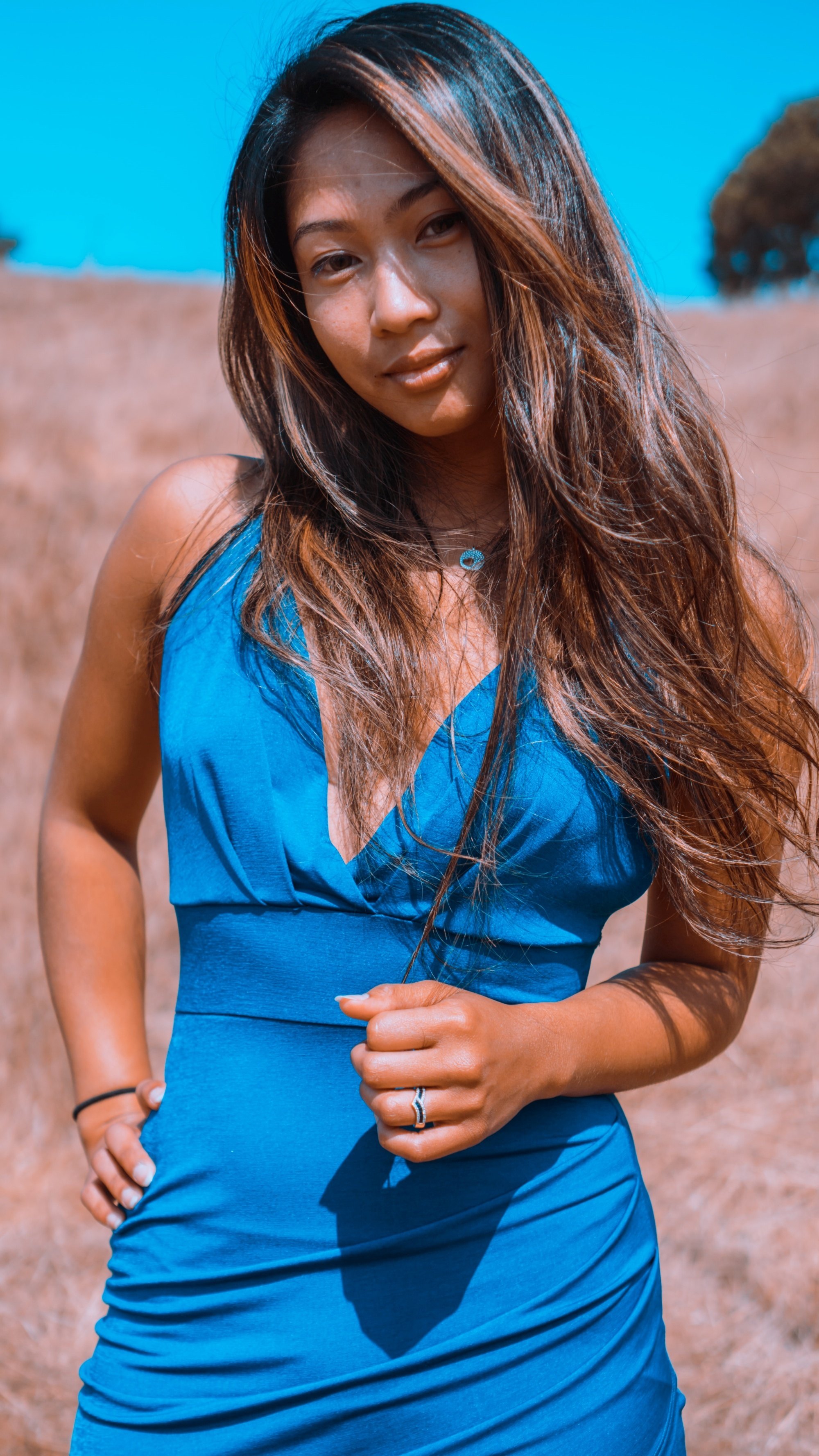 Asian woman with morena skin and long dark hair wearing a blue dress