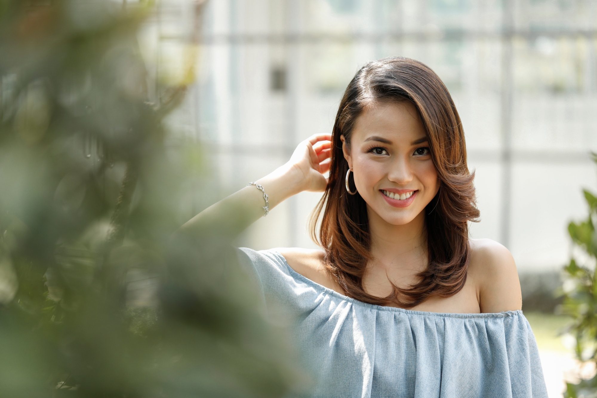 Asian woman with balayage brown hair wearing a blue off-shoulder top