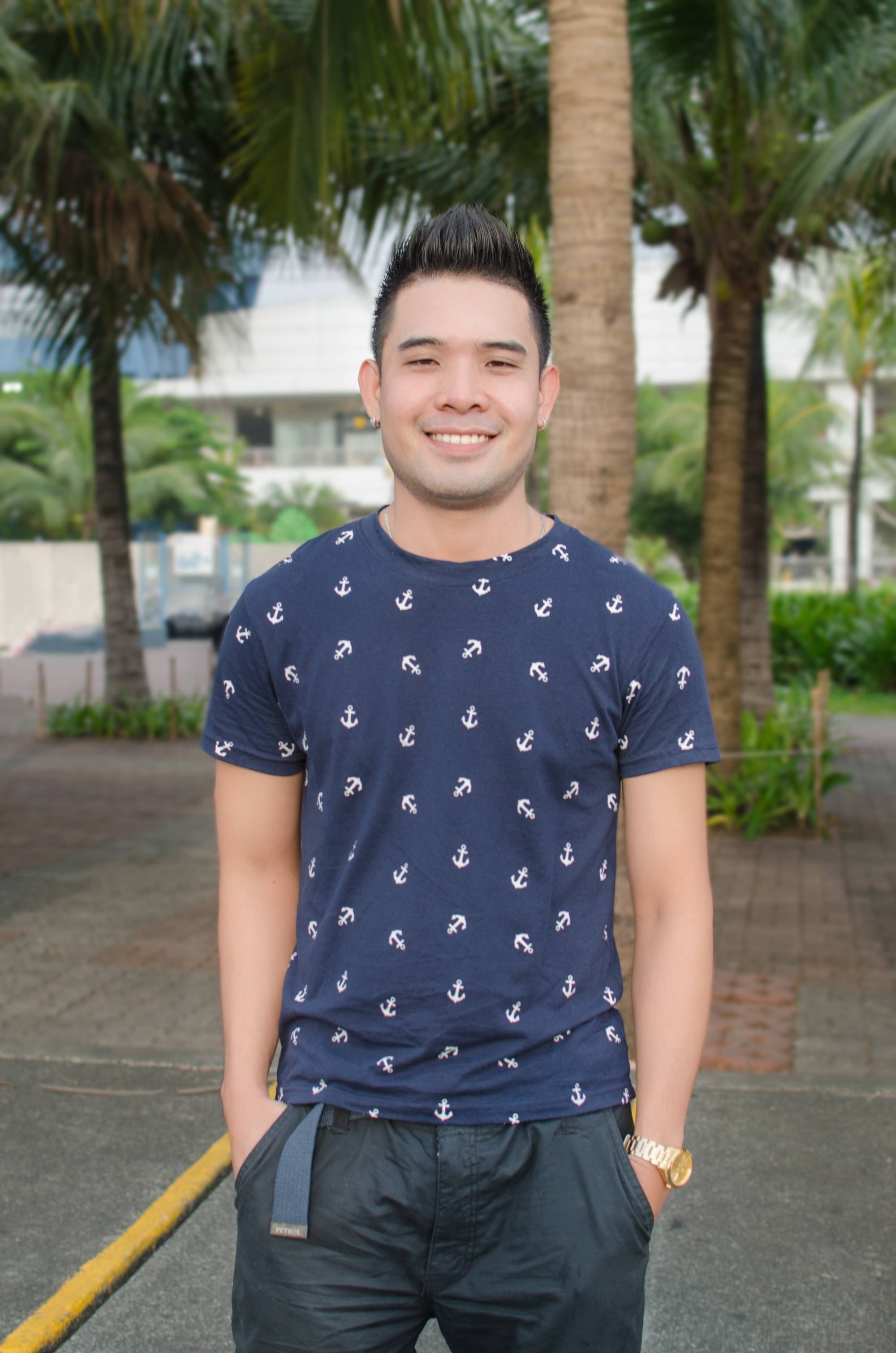 Filipino man with short hair wearing a blue shirt outdoors