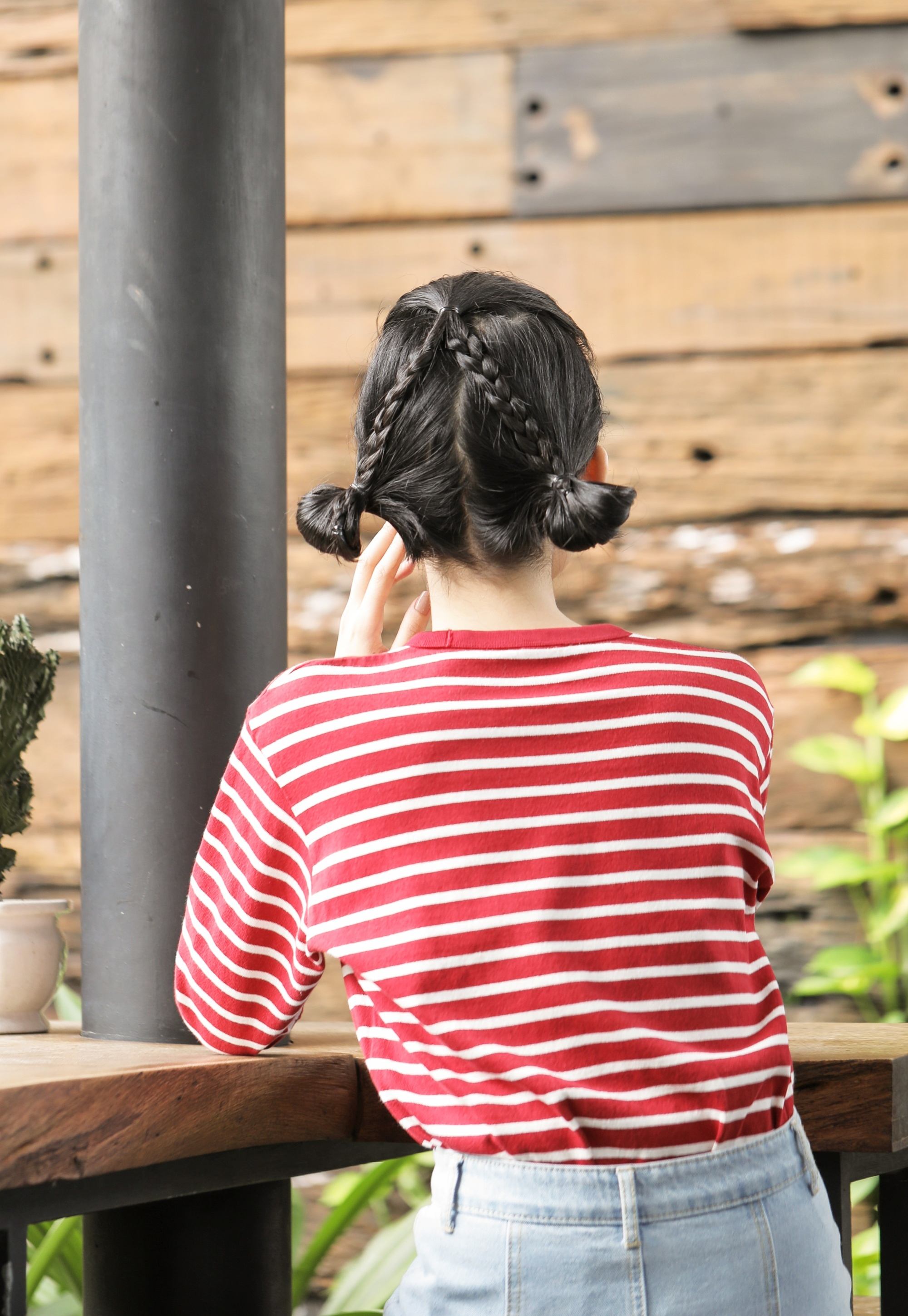 Back shot of an Asian woman with bun hairstyle wearing a red shirt