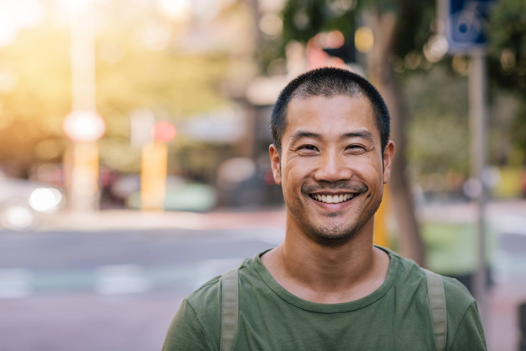 Asian man with buzz cut wearing a green shirt outdoors