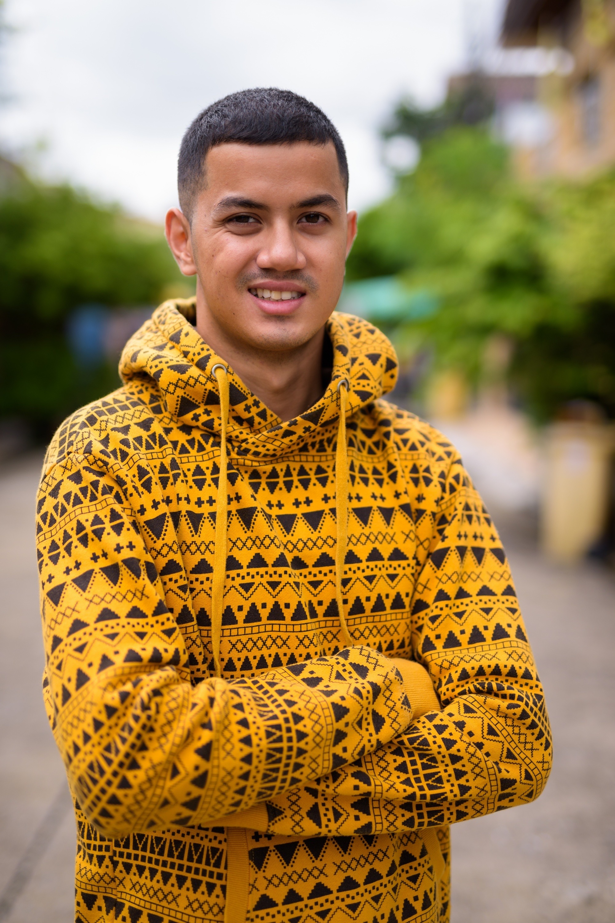 Asian man with a military trim haircut wearing a yellow jacket outdoors