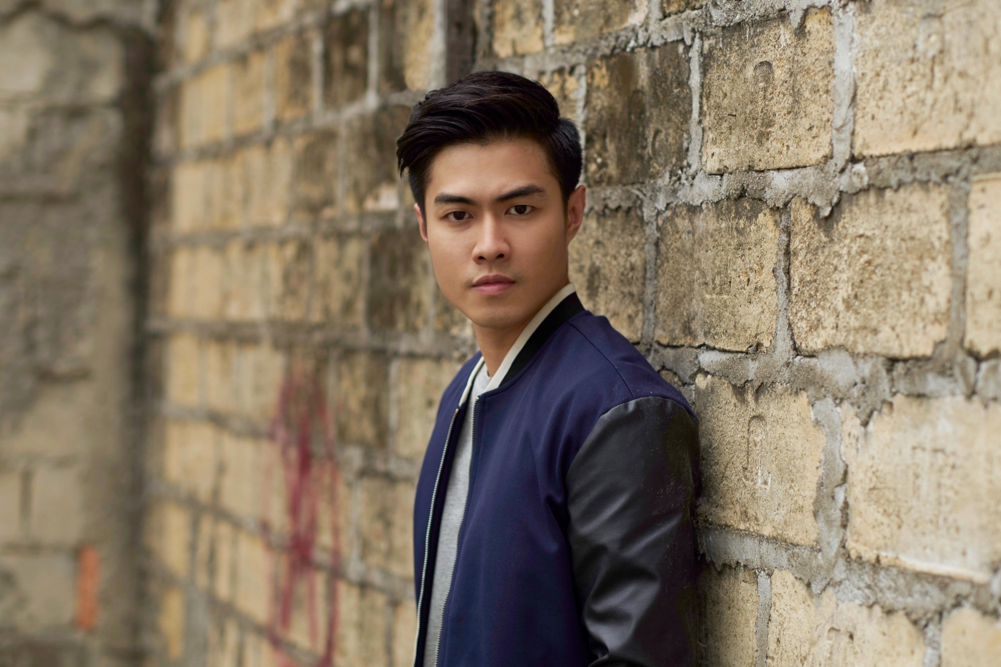 Asian man with short hair wearing a dark blue jacket