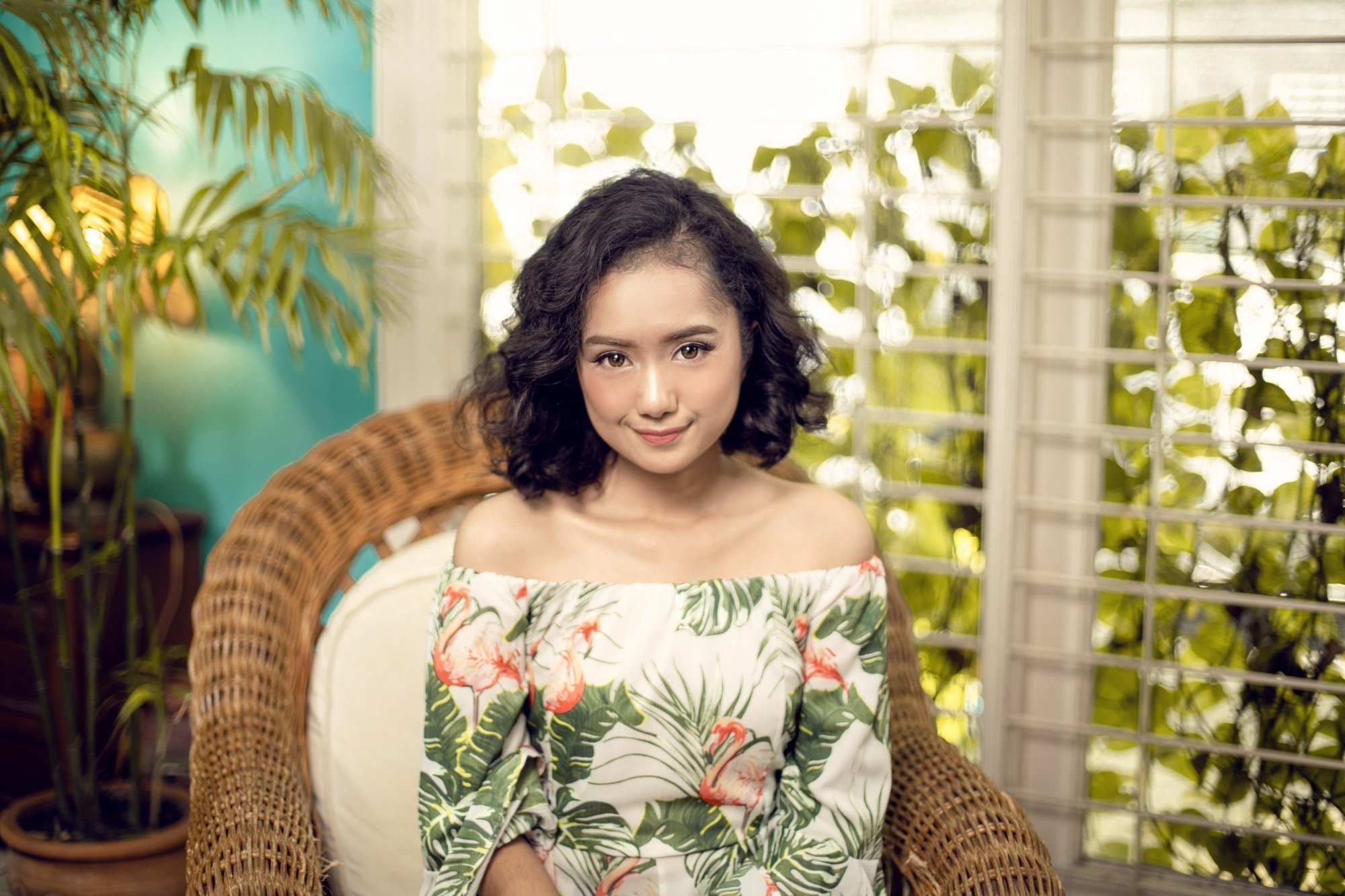 Asian woman with short curly hair wearing a green floral dress