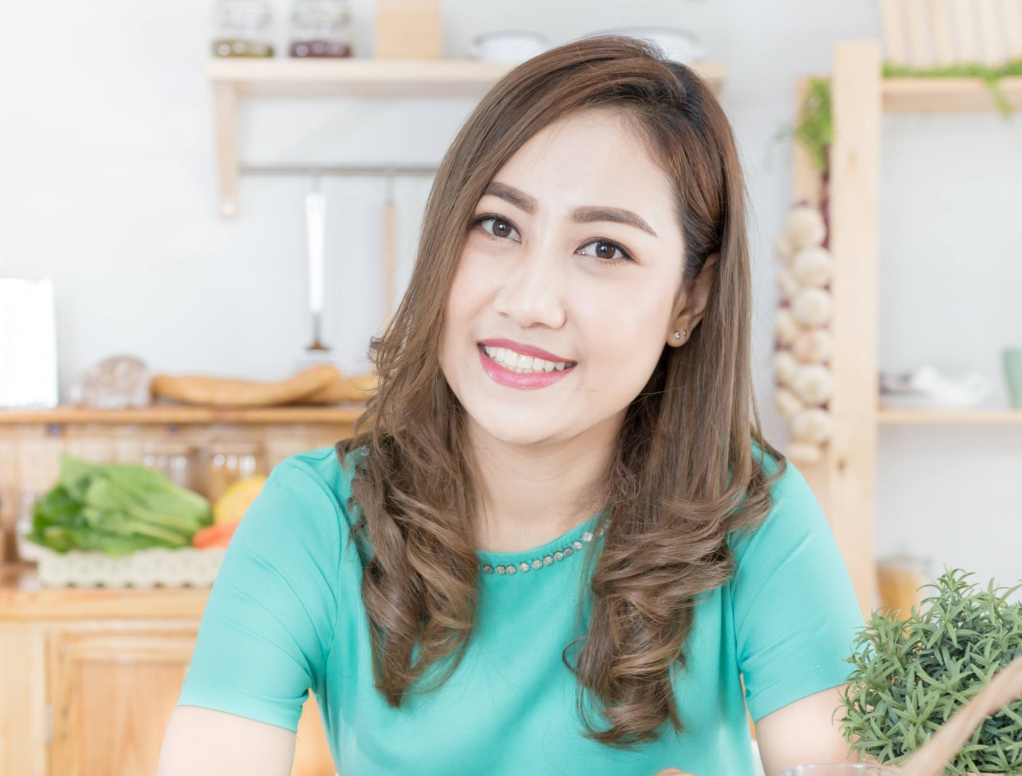 Asian woman with long ash brown hair wearing a blue-green shirt