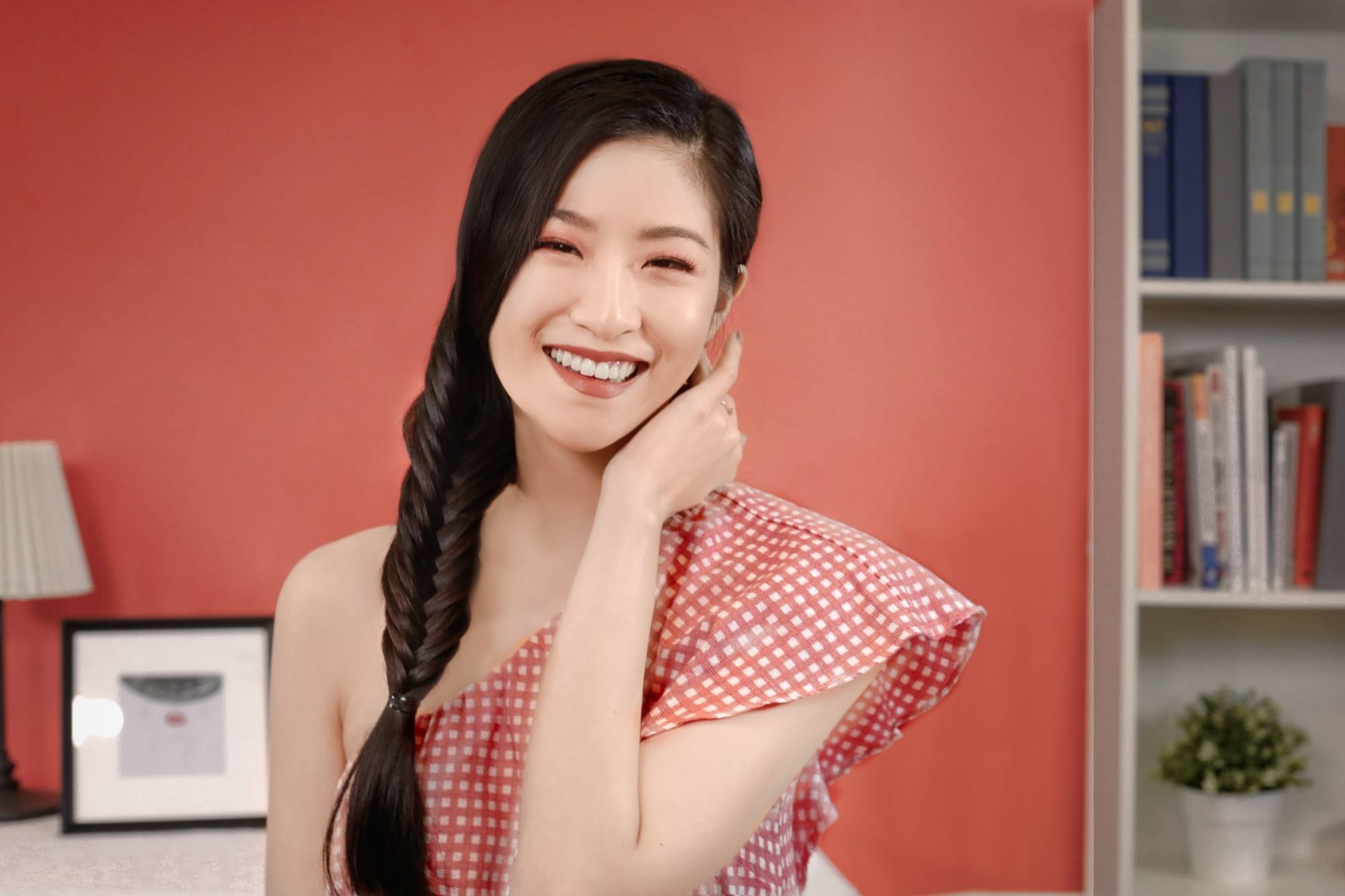 Asian woman with long hair in a side fishtail braid wearing a red top