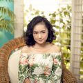 Asian woman with short curly hair sitting on a chair