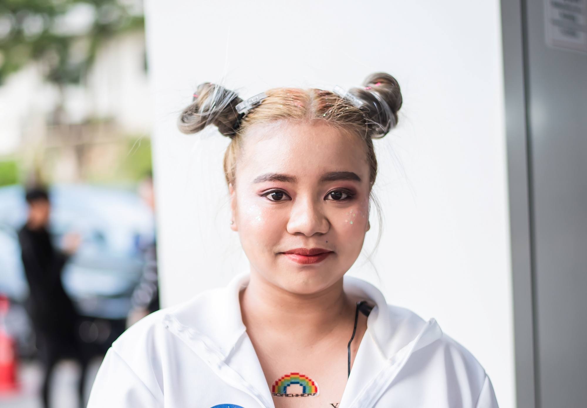 Asian woman with hair in space buns wearing a white jacket