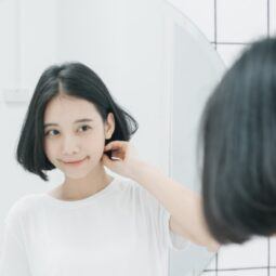 Asian woman with short hair looking in the mirror for a shampoo for seborrheic dermatitis concept