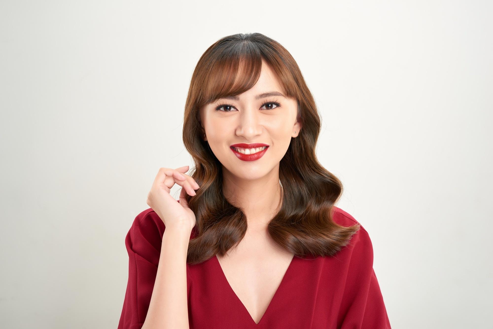 Asian woman with long wavy brown hair wearing a red blouse