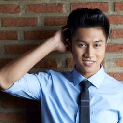 Asian man with a pompadour hairstyle wearing a polo and a tie.