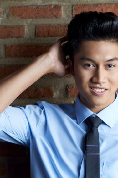 Asian man with a pompadour hairstyle wearing a polo and a tie.
