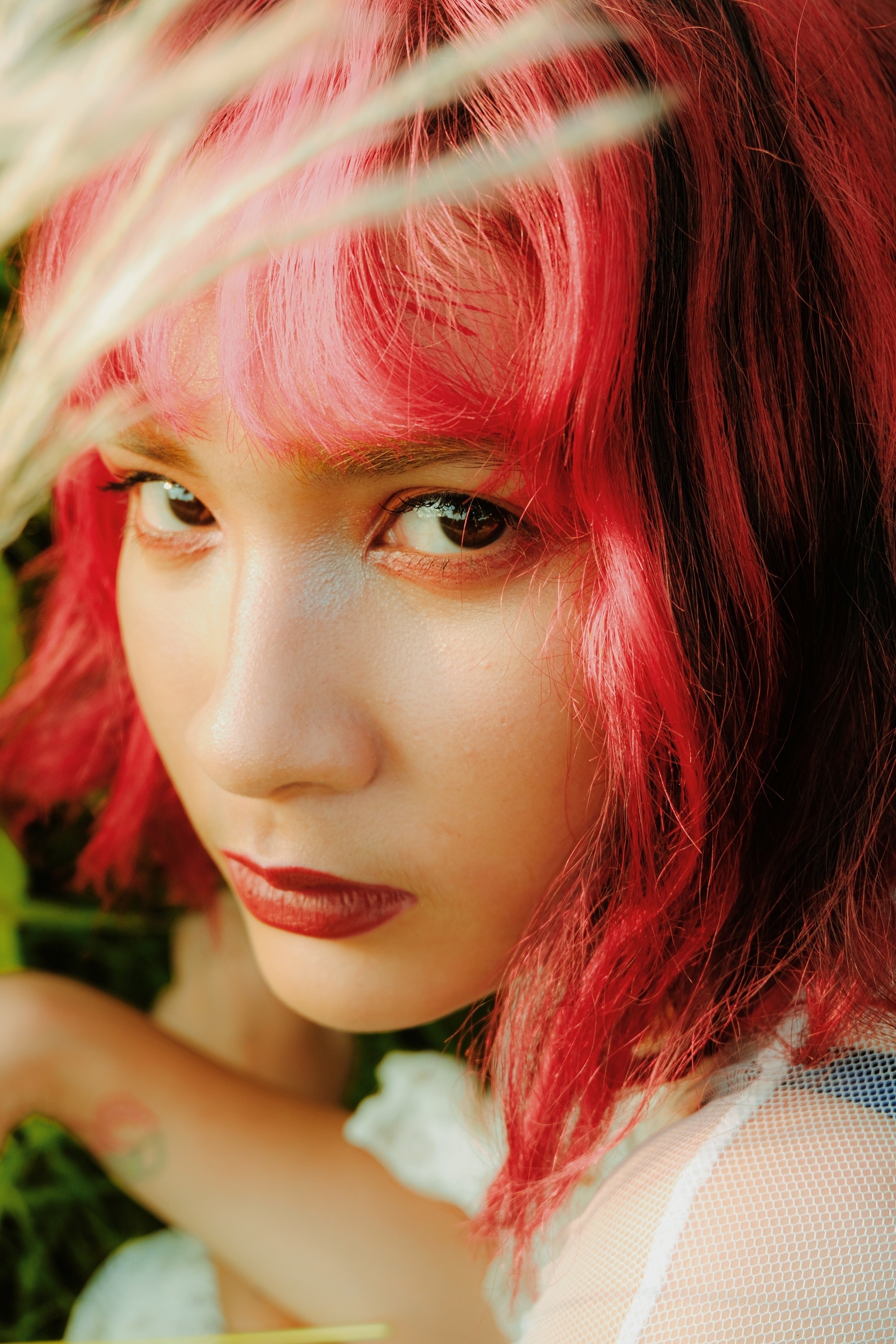 Asian woman with short wavy raspberry red hair with bangs