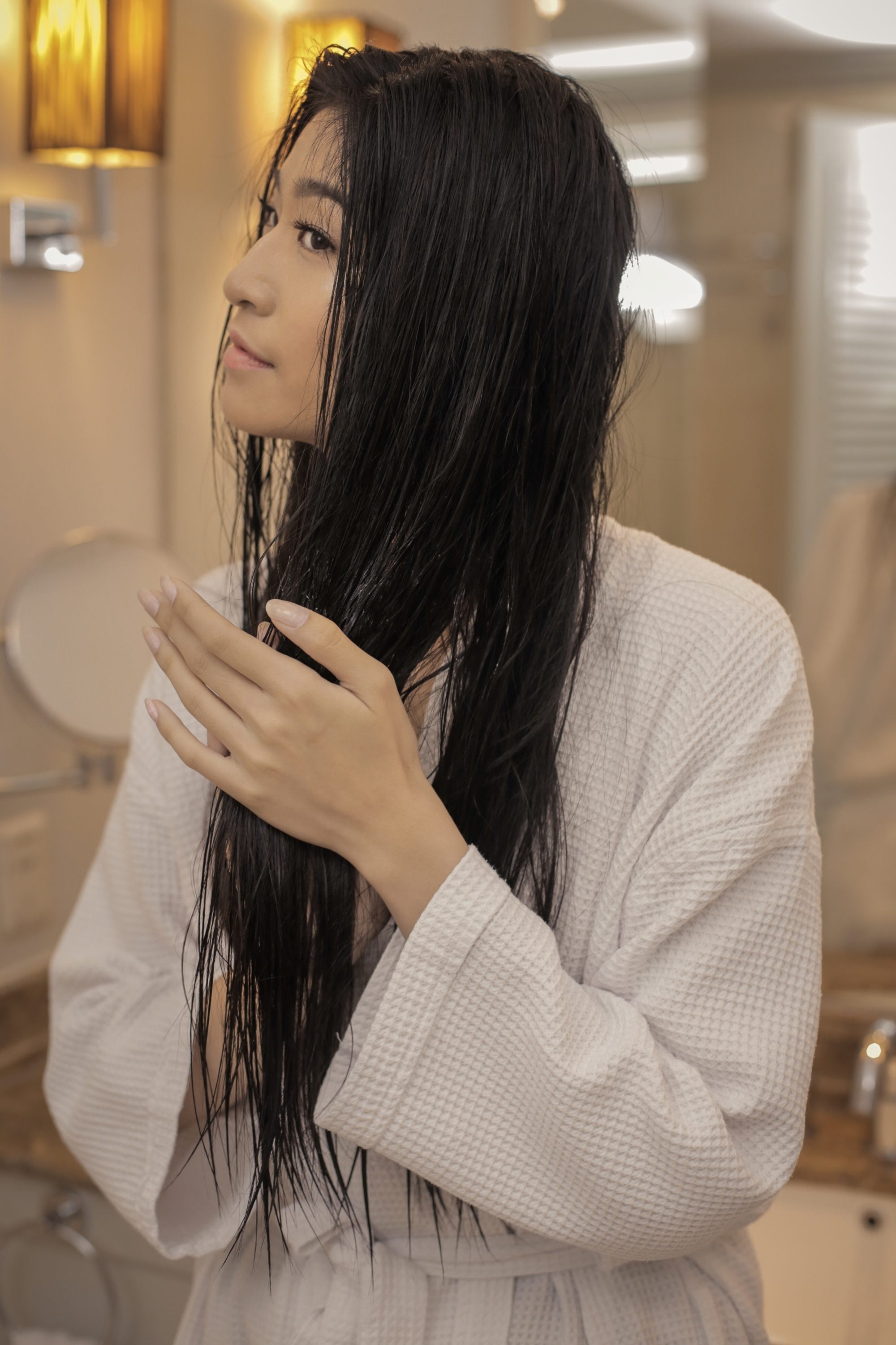 Asian woman applying treatment to brittle hair