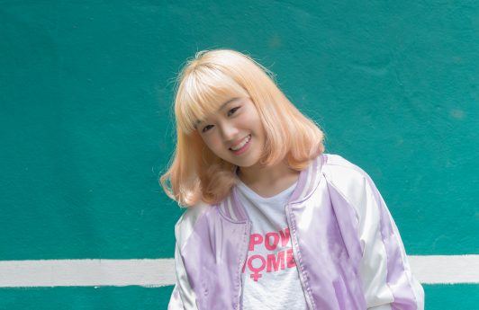 Asian woman with bleached blonde hair smiling