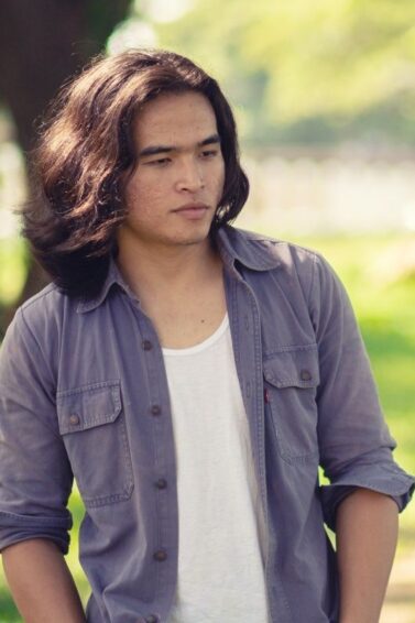 Asian man with long hair standing outdoors
