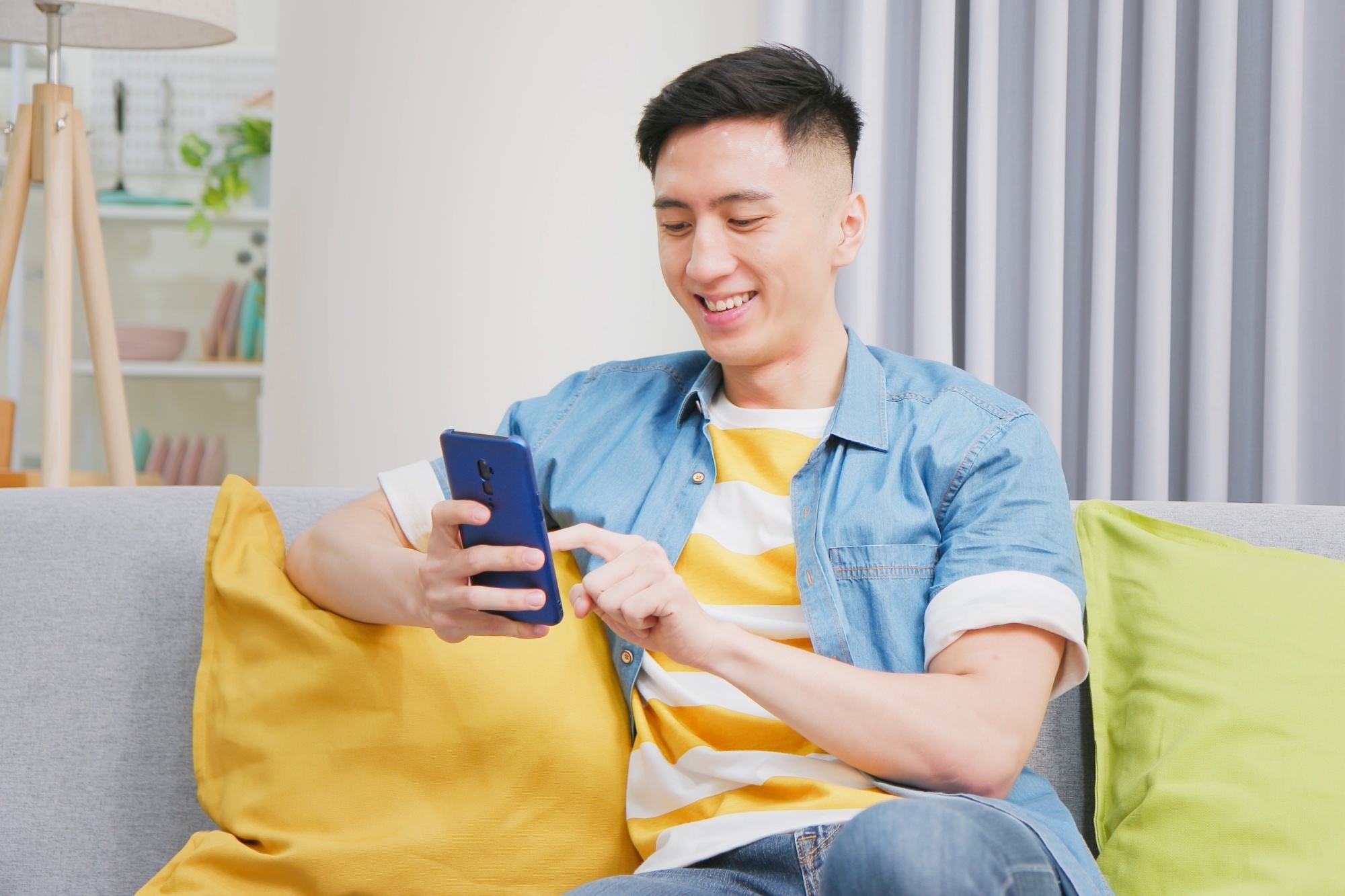Asian man with an undercut fade haircut using his cellphone