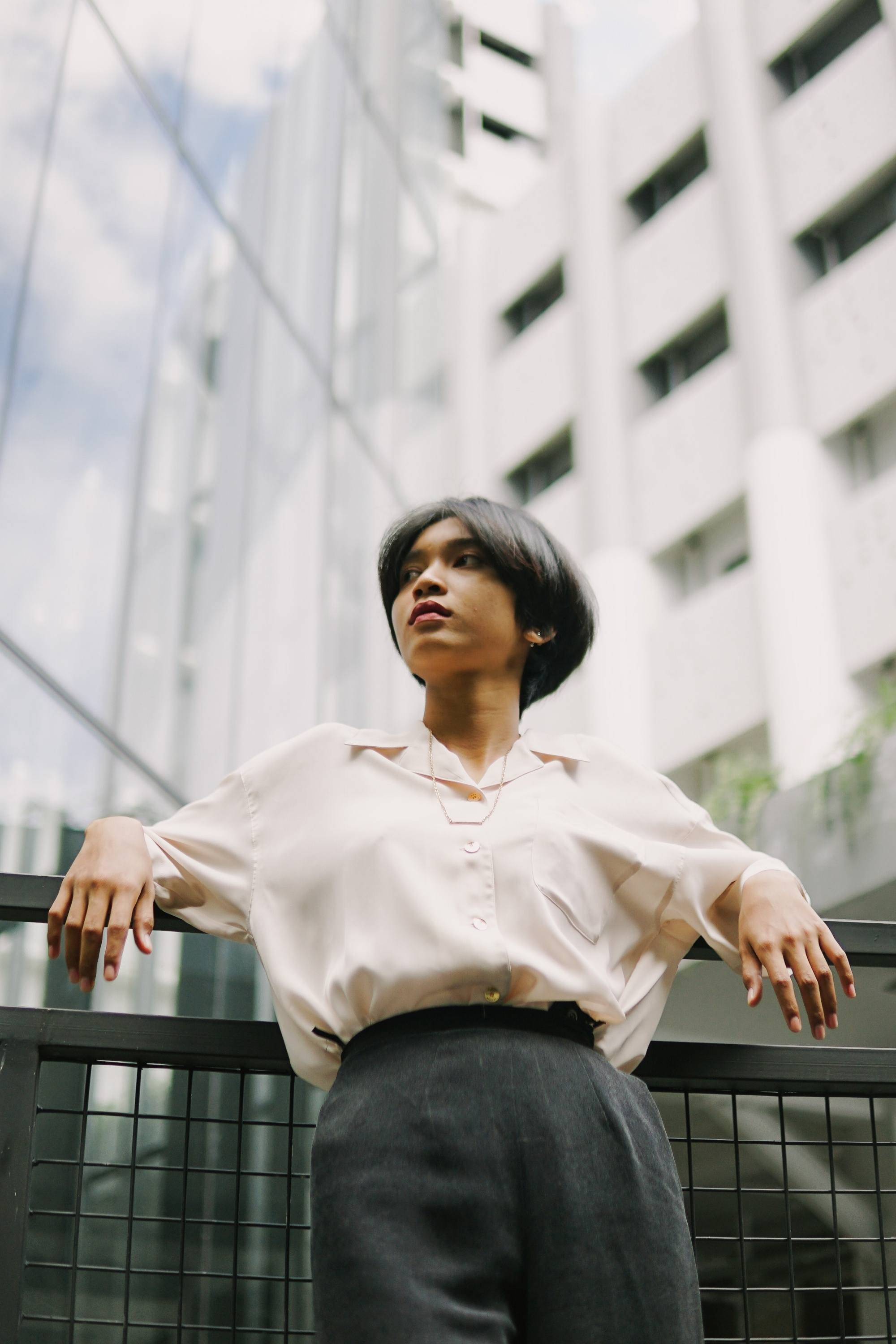 Asian woman with short hair standing against a background of buildings