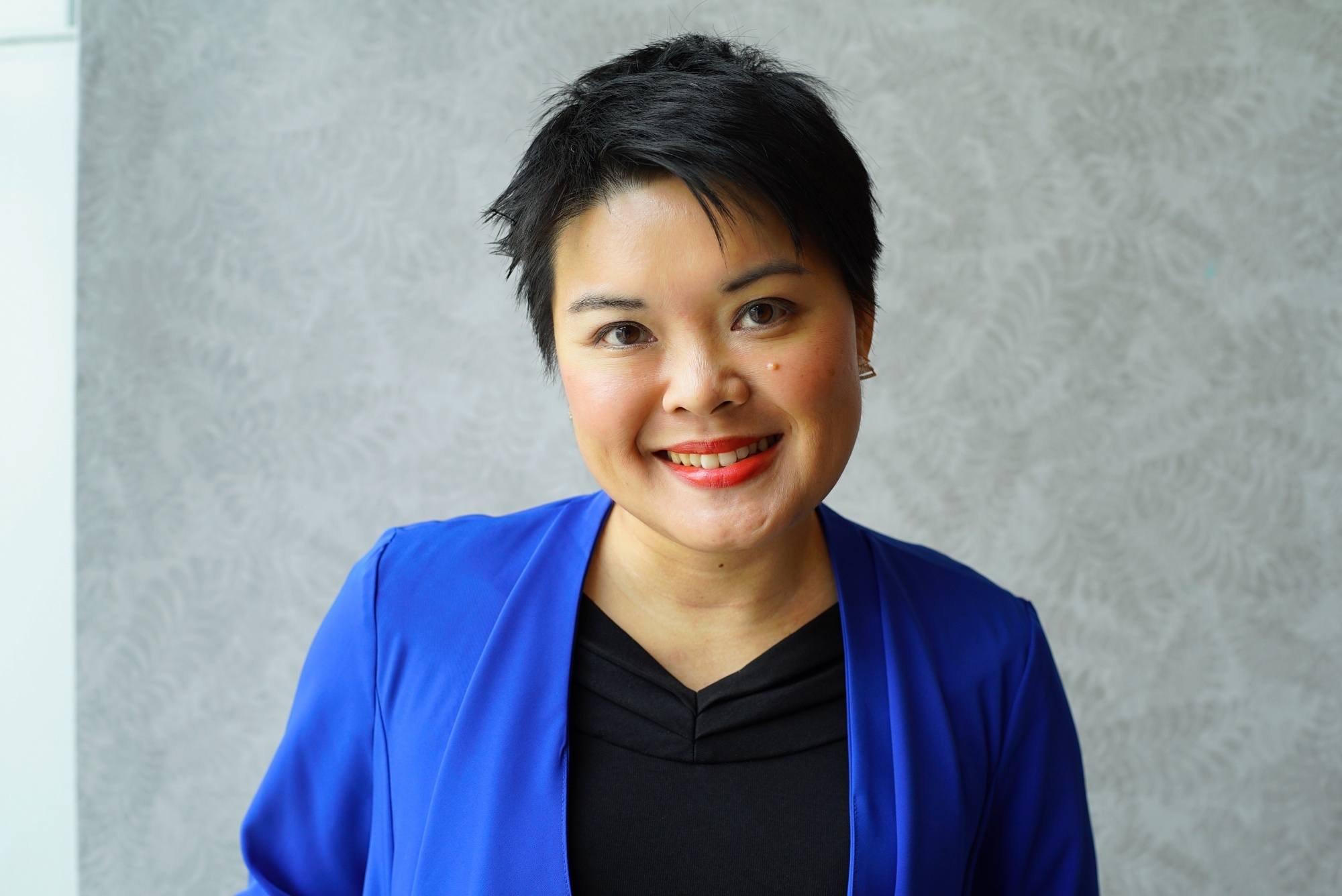 Asian woman with a short pixie cut smiling