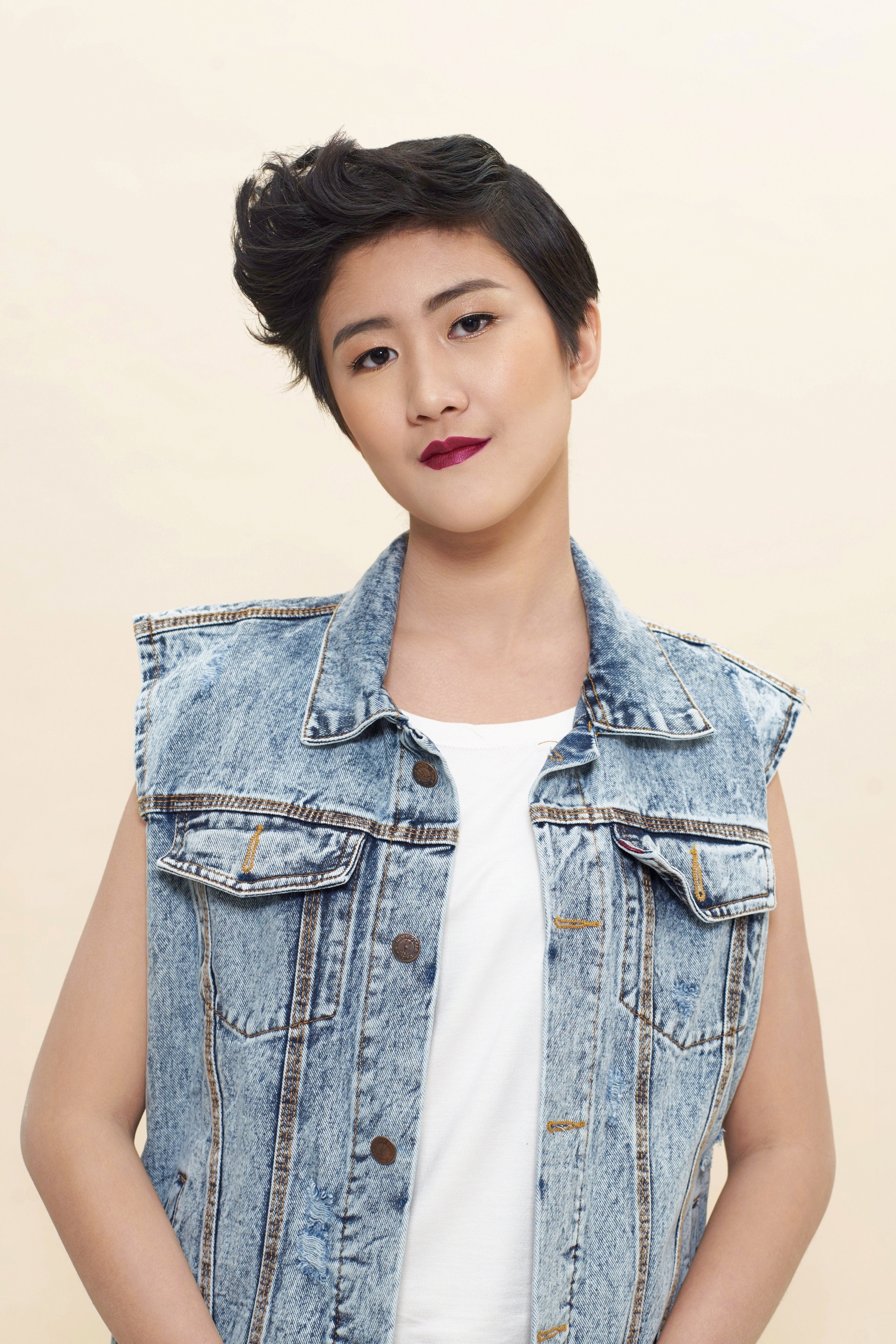 Asian woman with short hair wearing a denim vest