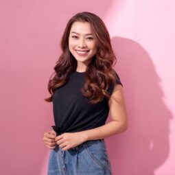 Asian woman with a beautiful hair color smiling against a pink background