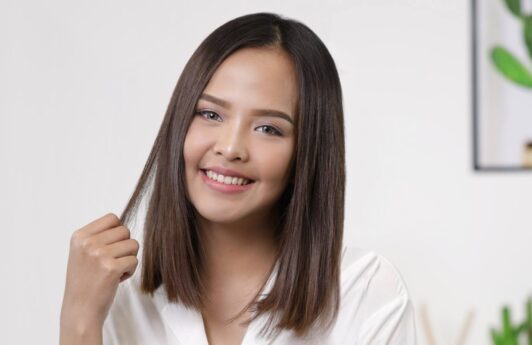 Asian woman holding a small section of her straight hair