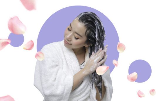 Natural beauty: Asian woman shampooing her hair with petal elements around her