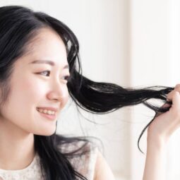 Asian woman looking at her hair for an anti-dandruff shampoo concept