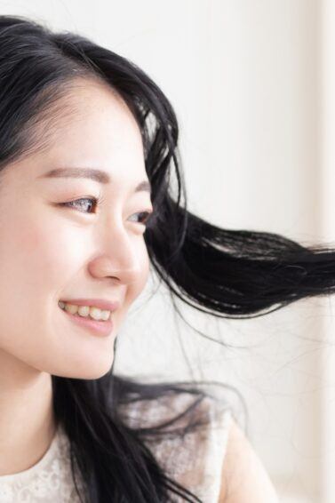 Asian woman looking at her hair for an anti-dandruff shampoo concept