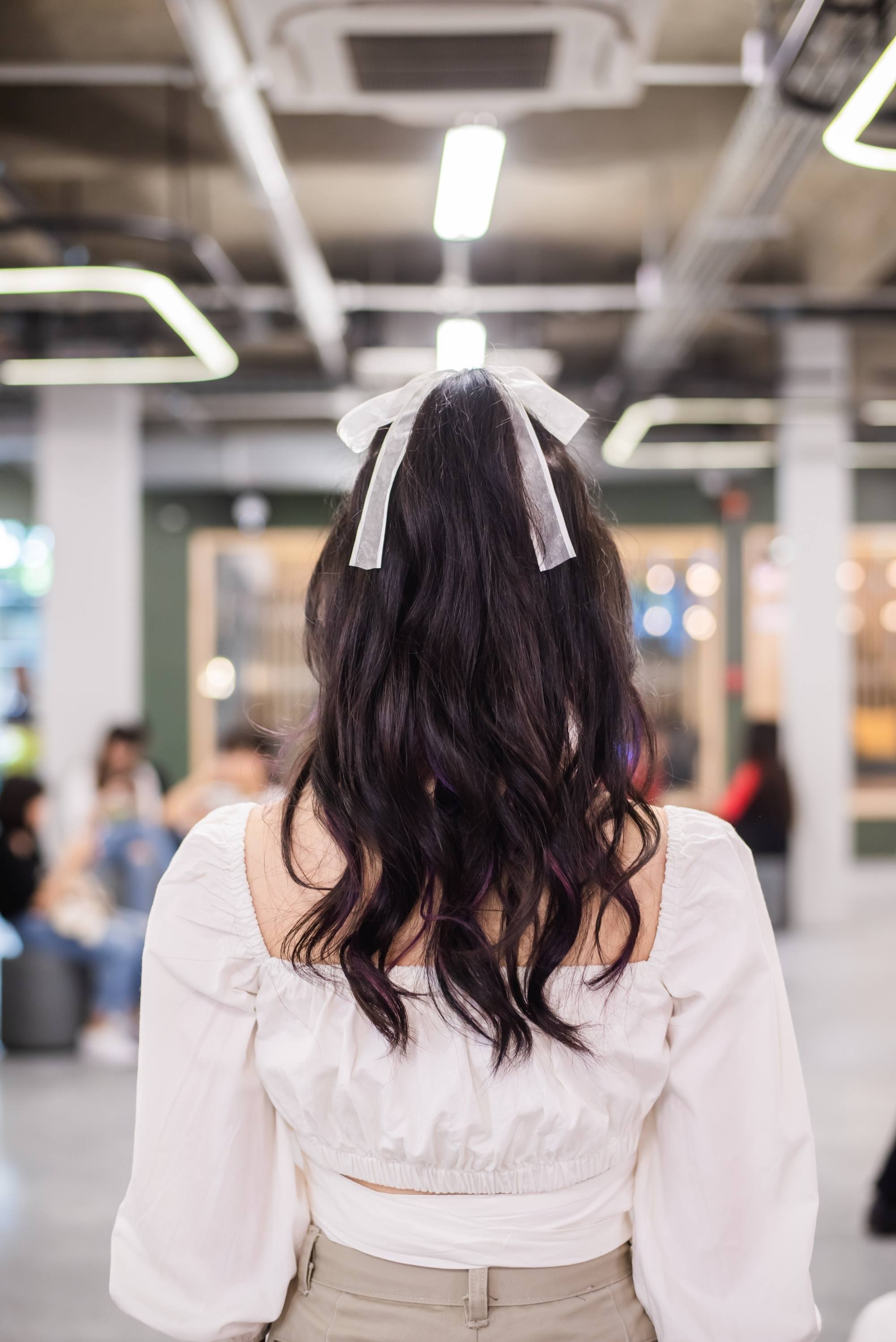 Back shot of an Asian woman with long wavy hair in a half ponytail