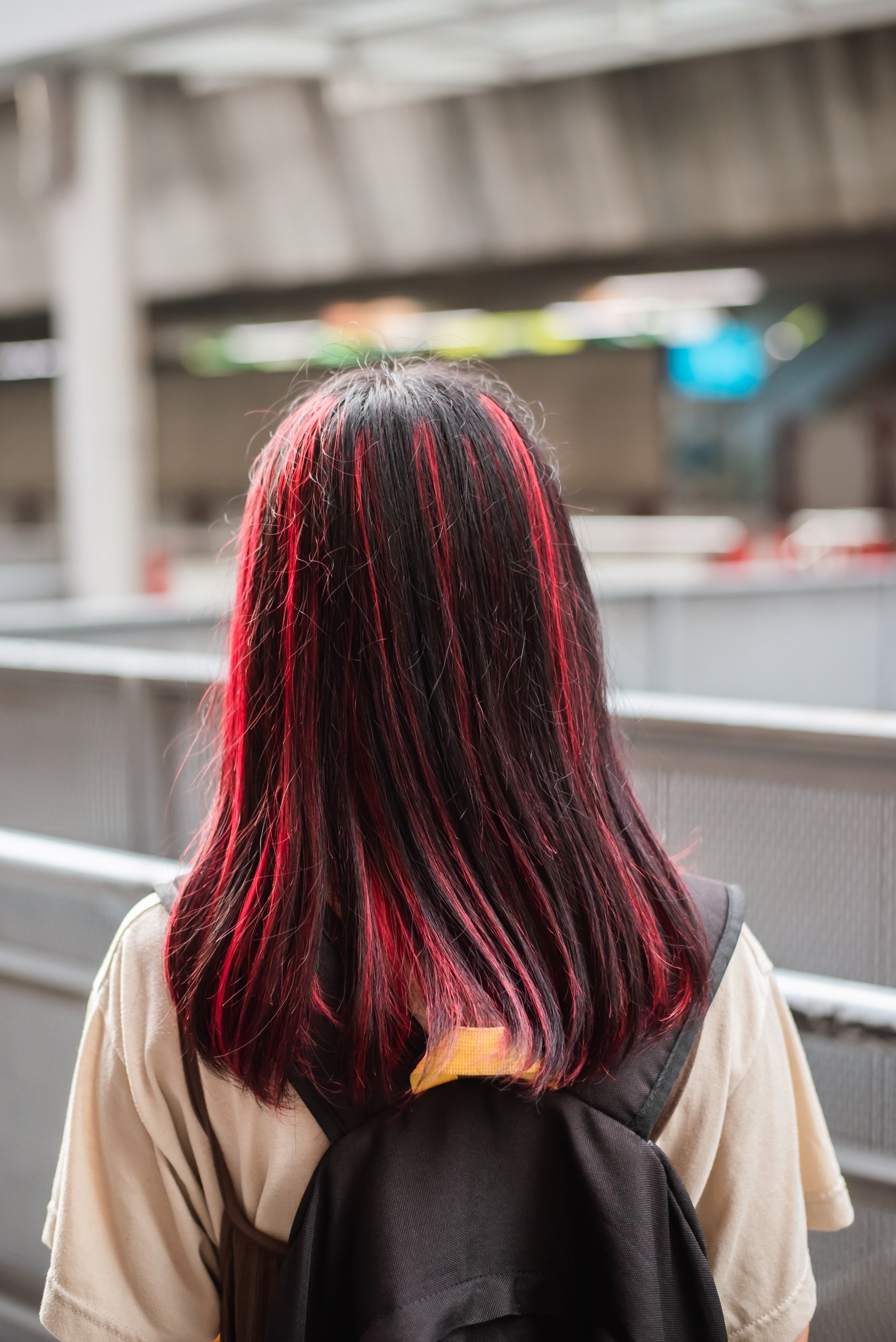 Back shot of an Asian woman with dark hair with red highlights