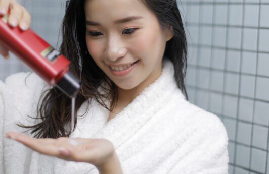 Asian woman pouring shampoo onto her palm for a shampoo ingredients concept