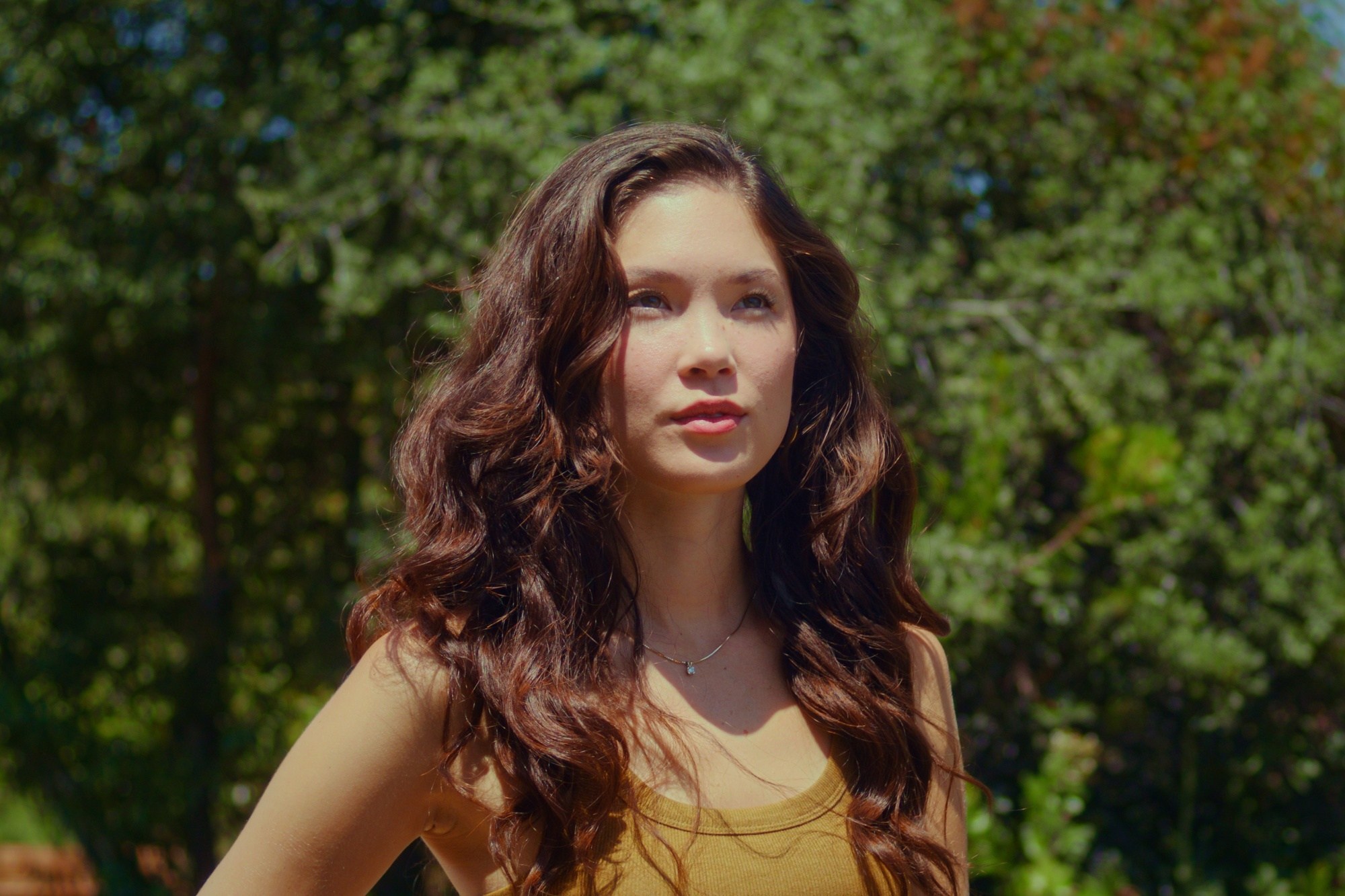 Asian woman with long curly hair showing a natural aesthetic hair trend