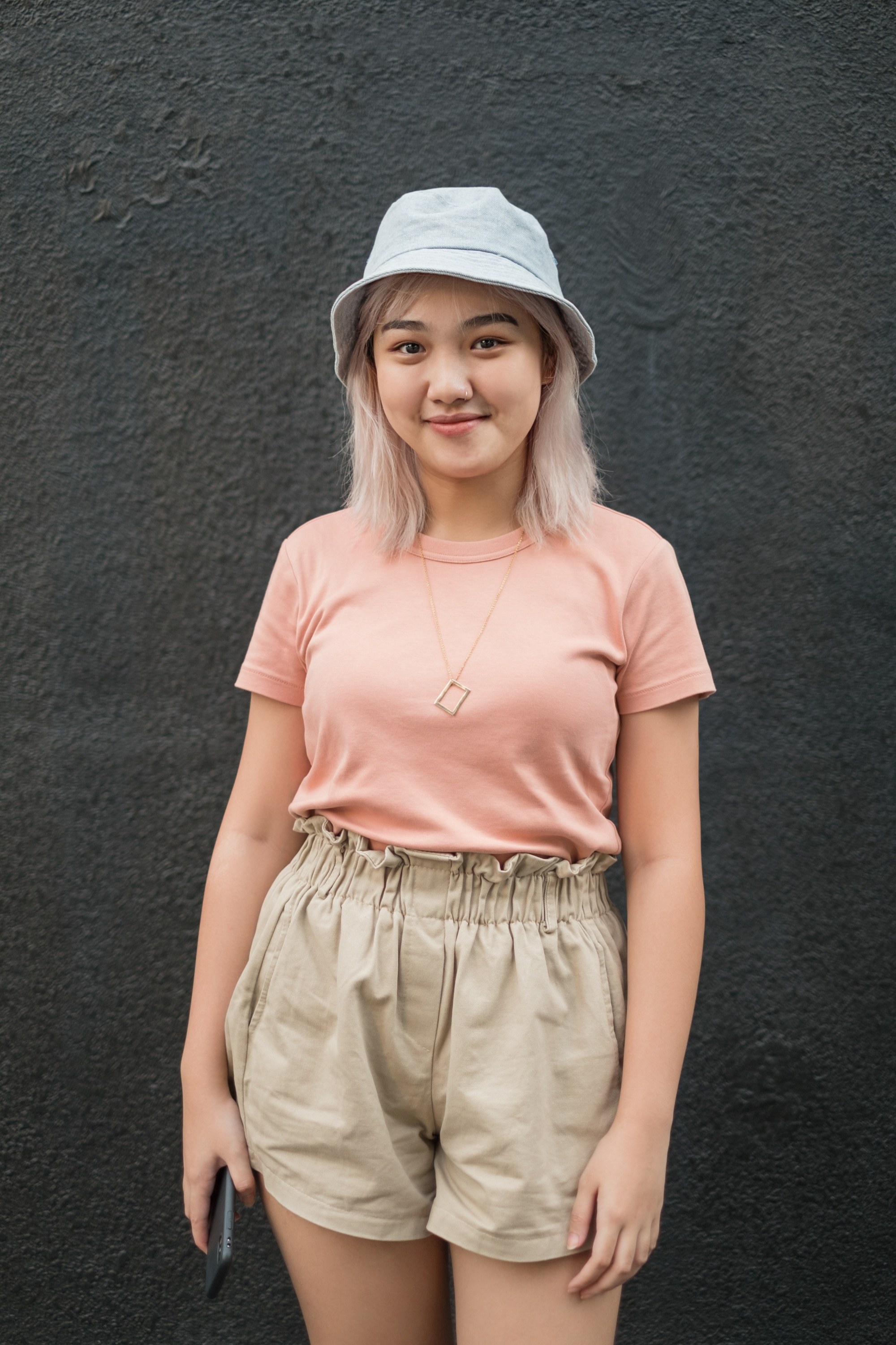 Asian woman with short platinum blonde hair wearing a bucket hat